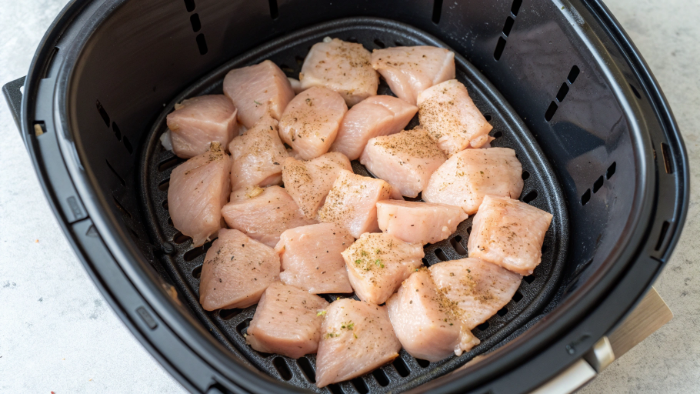 Chicken cubes inside air fryer basket before cooking